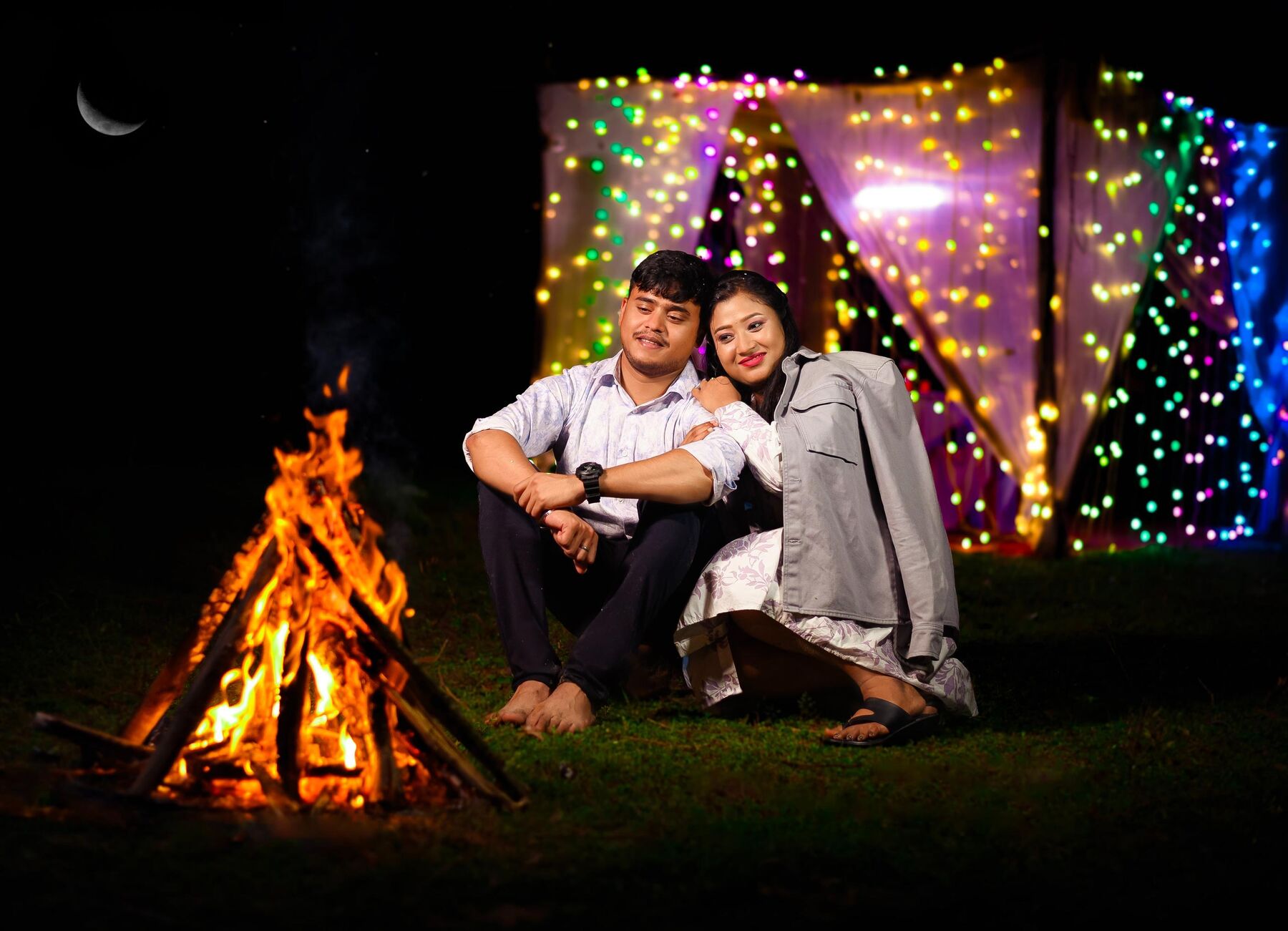 Couple by a bonfire under string lights